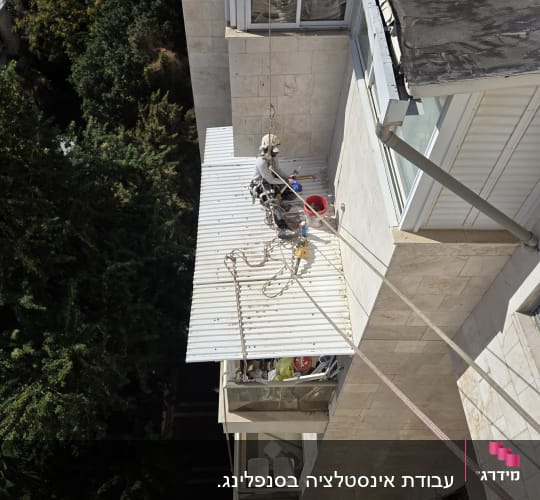 עובד בגובה על פיגום חיצוני עם ציוד בטיחות
